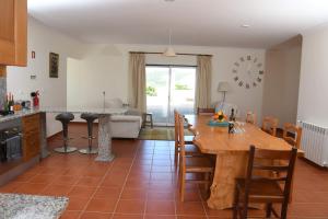 cocina y sala de estar con mesa de madera y sillas en Casa de Sandoeira, en Rego da Murta