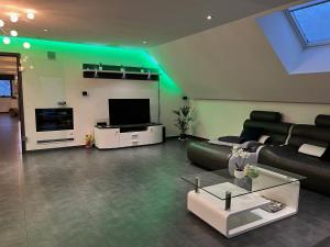uma sala de estar com um sofá preto e uma televisão em Loft de prestige au pied du circuit em Francorchamps