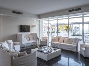 una sala de estar con muebles blancos y ventanas grandes. en La Chiave dei Trabocchi en San Vito Chietino