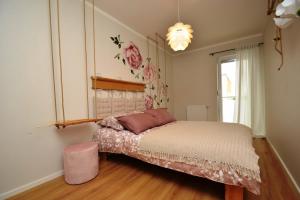 Schlafzimmer mit einem Bett mit einem rosa Stuhl und einem Fenster in der Unterkunft Przytulny Apartament Słowackiego in Wągrowiec