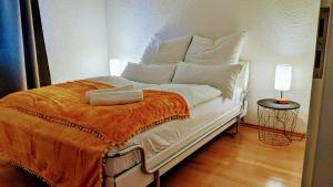 Cama blanca con almohadas blancas y manta naranja en Ruhige, moderne Wohnung bei Darmstadt in Roßdorf, en Roßdorf