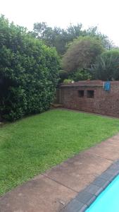 a backyard with a brick wall and a grass yard at Me, myself, I Glamping in Pietermaritzburg