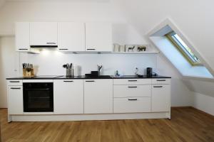 a kitchen with white cabinets and a stove at Tannenhof Fischbach - Fewo 5 "Zander" - Schluchsee, 2 Schlafzimmer Schlafgalerie, E-Auto Ladestation in Schluchsee