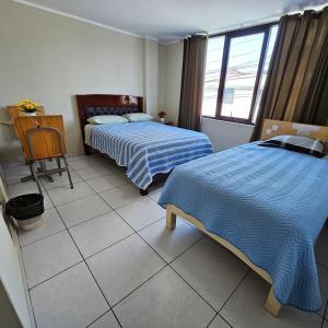 a room with two beds and a table with a desk at Hostal Santa Barbara in Ilo