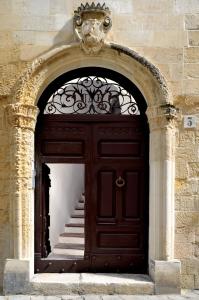 une grande porte en bois avec des escaliers en face d'un bâtiment dans l'établissement Palazzo Rudiae - Sant'Irene, à Lecce