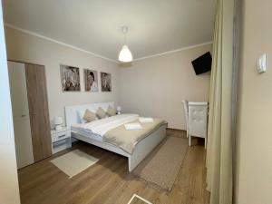 a bedroom with a white bed and a mirror at Airport Alexandra Apartments in Surčin