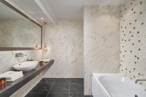 a white bathroom with a tub and a sink at Arte & Mare Elia Luxury Suites and Villas in Elia Beach