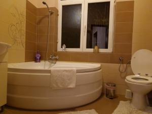 baño con bañera, aseo y ventana en M&A Mario Ultra Central Apartament, en Brasov