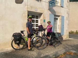 two people standing with their bikes in front of a building at Logis des Lauriers Roses in Marennes