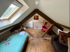 een kamer met een bed en een stoel op zolder bij Bridgend Cottage in Abercraf