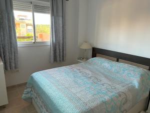 - une chambre avec un lit doté d'une couette bleue et d'une fenêtre dans l'établissement Casares Del Sol Apartment Pearl, à Bahia de Casares