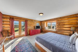 - une chambre avec un lit, des murs en bois et des fenêtres dans l'établissement Teton Pass Perch, à Victor