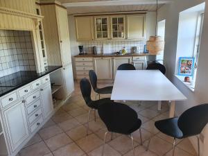 eine Küche mit einem weißen Tisch und schwarzen Stühlen in der Unterkunft Slotsgaardens feriegård. in Jels