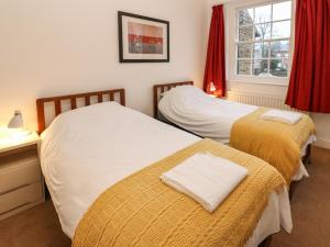 two beds in a room with a window at Cedars in Penrith