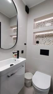 a white bathroom with a toilet and a mirror at Pokoje Goscinne SALOMEA in Karwia +37 photos