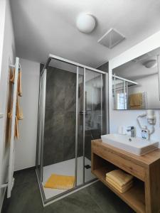 bagno con doccia in vetro e lavandino di Ferienhof zur Sonne a Tux