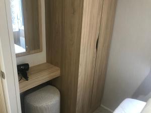 a small room with a wooden cabinet and a mirror at Captivating 3-Bed brand new Luxury Caravan in Skipsea