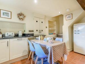 a kitchen with a table with blue chairs and a white refrigerator at Mulberry Cottage in Bakewell