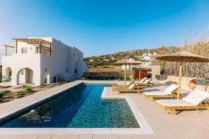 una villa con piscina con sedie e ombrelloni di Villa Finest -Seaside Villa with private swimming pool- a Mikri Vigla