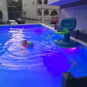 a young child swimming in a swimming pool with a water toy at Apartments Vila Adrijana & Fitness Studio WOLF BV in Baška Voda