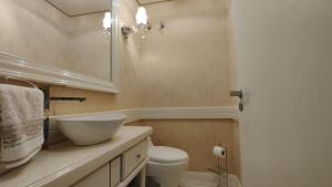 a bathroom with a sink and a toilet and a mirror at Amplo apartamento 03 dorm Centro de Gramado in Gramado
