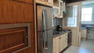 a kitchen with a stainless steel refrigerator and wooden cabinets at Amplo apartamento 03 dorm Centro de Gramado in Gramado