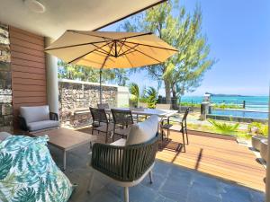 een patio met een tafel en stoelen en een parasol bij Idyllic Beach Apartment in Bain Boeuf