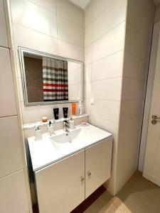 a white bathroom with a sink and a mirror at Appart Cosy pieds dans l'eau au coeur de Kantaoui in Sousse