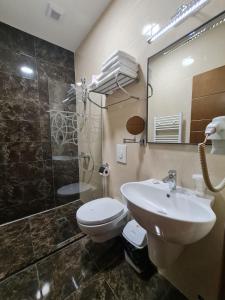 a bathroom with a sink and a toilet and a mirror at Hotel Angro Palace in Kavadarci