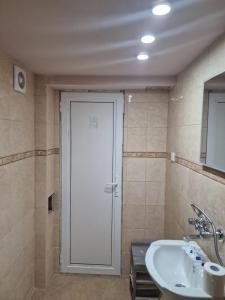 La salle de bains est pourvue d'une porte blanche et d'un lavabo. dans l'établissement Къща за гости Теяна, à Tryavna