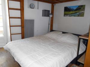 een slaapkamer met een wit bed met een klok aan de muur bij Appartement WIFI Monné centre Cauterets in Cauterets