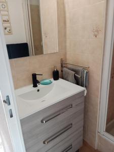 een badkamer met een witte wastafel en een spiegel bij Superbe appartement avec vue sur la mer et port in Frontignan