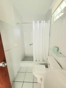 a white bathroom with a toilet and a shower at Nautilus by La Jamaca Hotels-Downtown La Parguera in Lajas