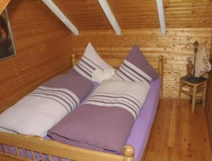 ein Bett in einem Blockhaus mit Kissen darauf in der Unterkunft Ferienhaus Glashütt in Sankt Englmar