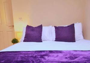 a bed with purple and white pillows in a room at Furley Road London Guest House in London