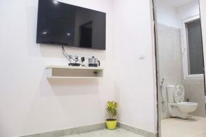 a bathroom with a toilet and a tv on the wall at JSB HOTEL in Faridabad