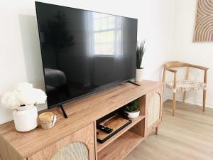 a large flat screen tv on a wooden entertainment center at Coastal Cottage By Vilano in St. Augustine