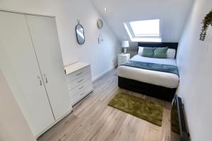 a bedroom with a bed and a dresser and a window at Luxury Two Bedroom Apartment Southsea in Portsmouth