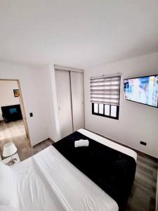 1 dormitorio con 1 cama y TV en la pared en El refugio paisa en Medellín