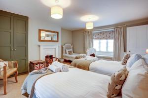 a bedroom with three beds and a fireplace at The Bladon Farmhouse in Woodstock
