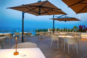 un ristorante con tavoli, sedie e ombrelloni di Girasole Eco Family Village a Marina Palmense