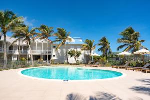 a swimming pool in front of a house with palm trees at Appartement Orient Bay-Ti Paradise in Saint Martin
