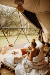 a woman sitting in a bed in a tent at Czorsztyn Glamp in Maniowy