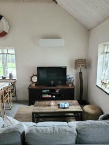 uma sala de estar com um sofá e uma televisão em Litet hus i mysig by nära havet em Ystad