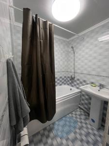 y baño con cortina de ducha, bañera y lavamanos. en Французский дом 47 en Shymkent