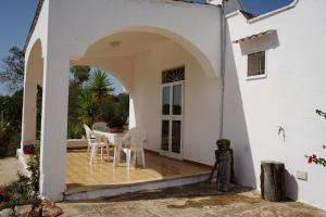 eine Terrasse in einem weißen Haus mit einem Tisch und Stühlen in der Unterkunft Casedda Gelsomino in Ostuni