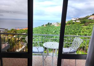 einen Balkon mit Aussicht, einem Tisch und Stühlen in der Unterkunft bluegreen in Arco da Calheta