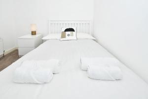 Cama blanca con sábanas y almohadas blancas en Squirrel Cottage by YourStays en Stoke on Trent