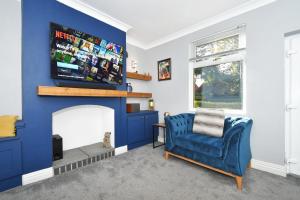 a blue living room with a tv above a fireplace at Squirrel Cottage by YourStays in Stoke on Trent