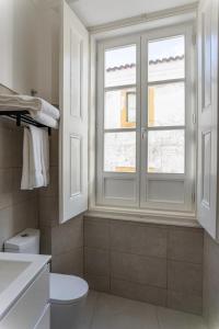 a bathroom with a white toilet and a window at Guest House - Palácio Diana in Évora